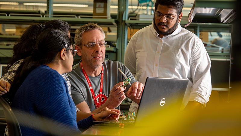 Professors working with students with electrical equipment