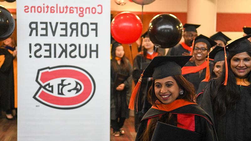 Graduates processing by branded sign